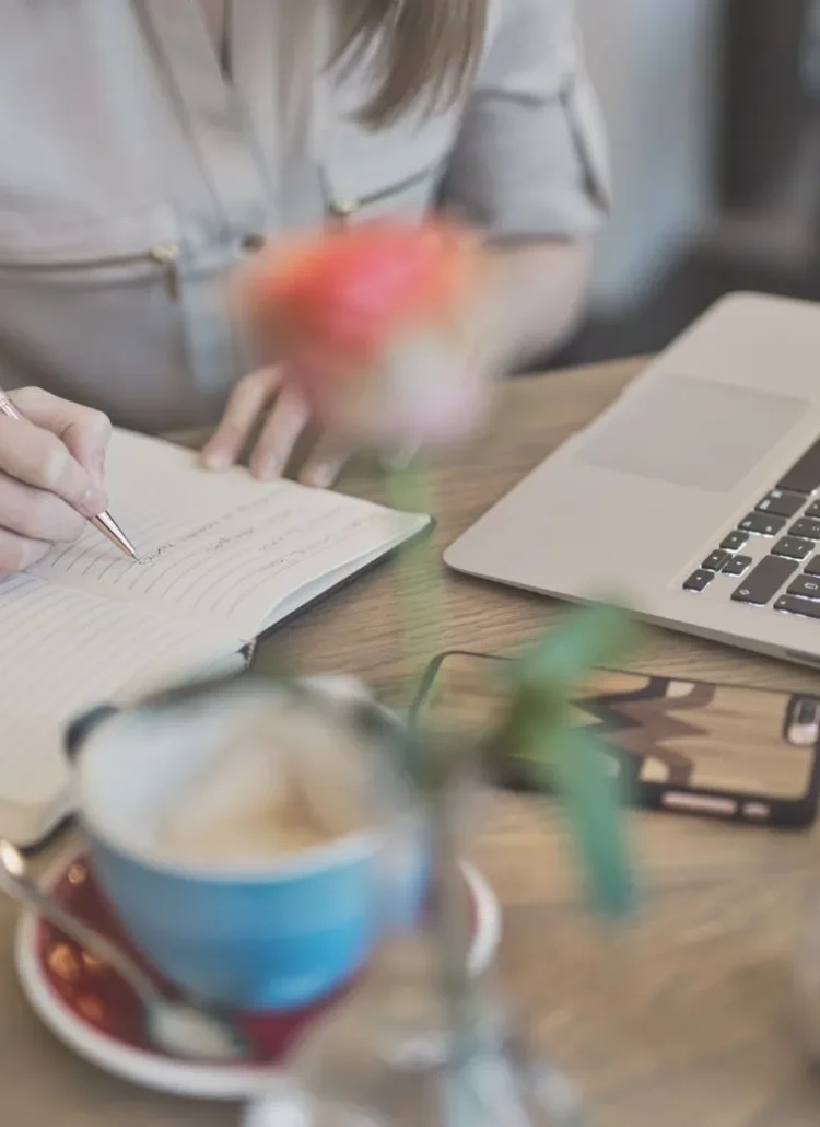 woman writing new month journal prompts in the background