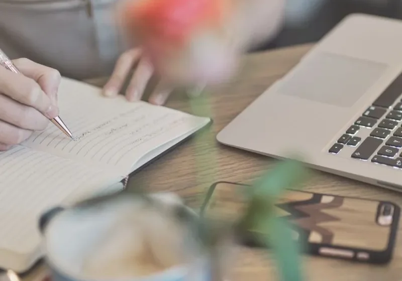 woman writing new month journal prompts in the background
