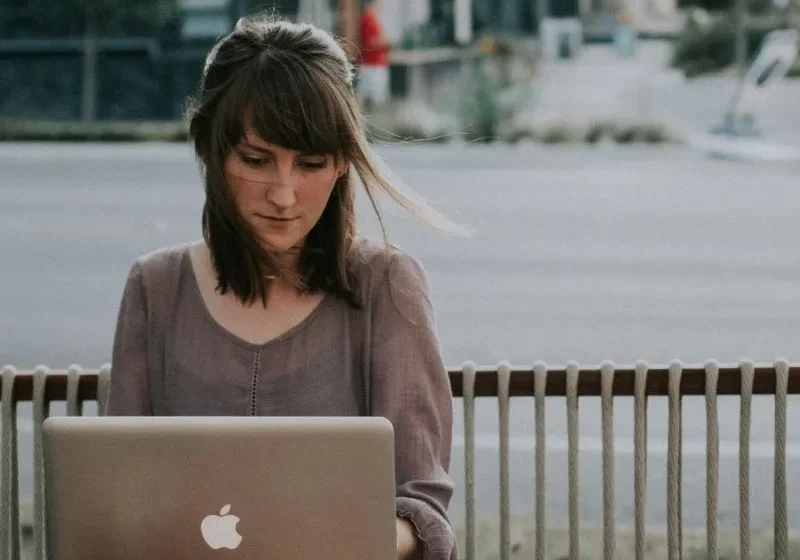 woman sitting in public with her Mac notebook