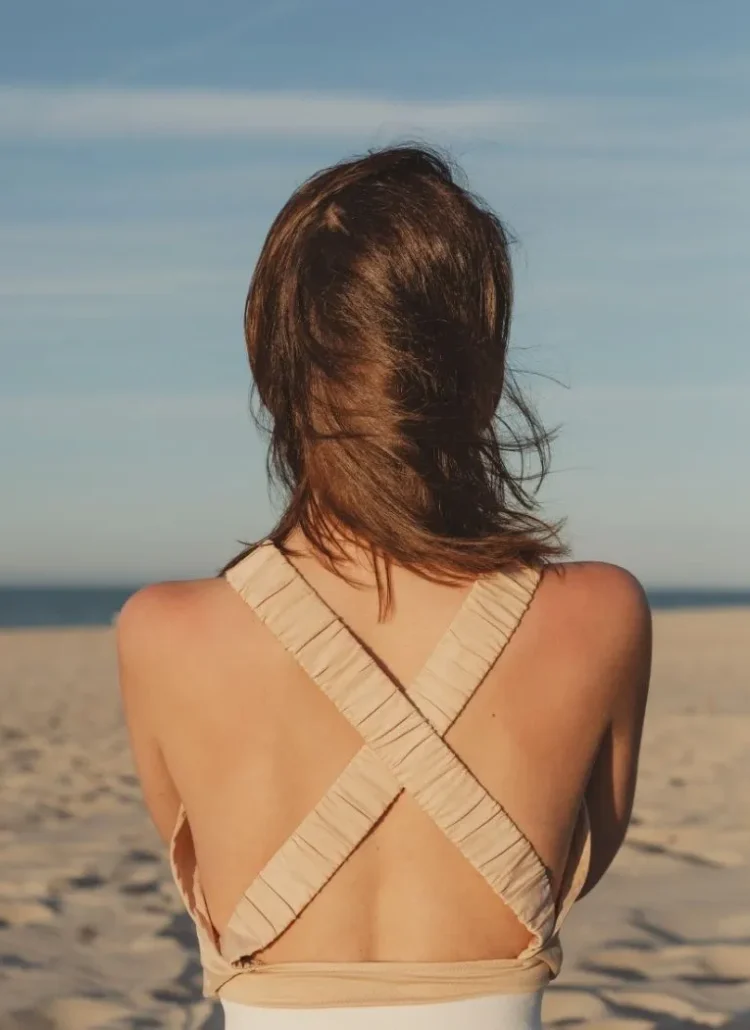 Woman looking out to the beach hugging herself