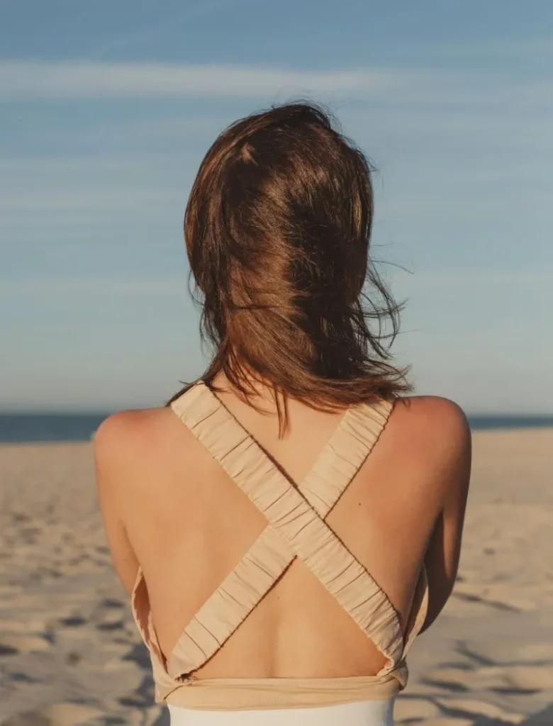 Woman looking out to the beach hugging herself