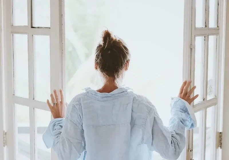 woman look out the window in the morning