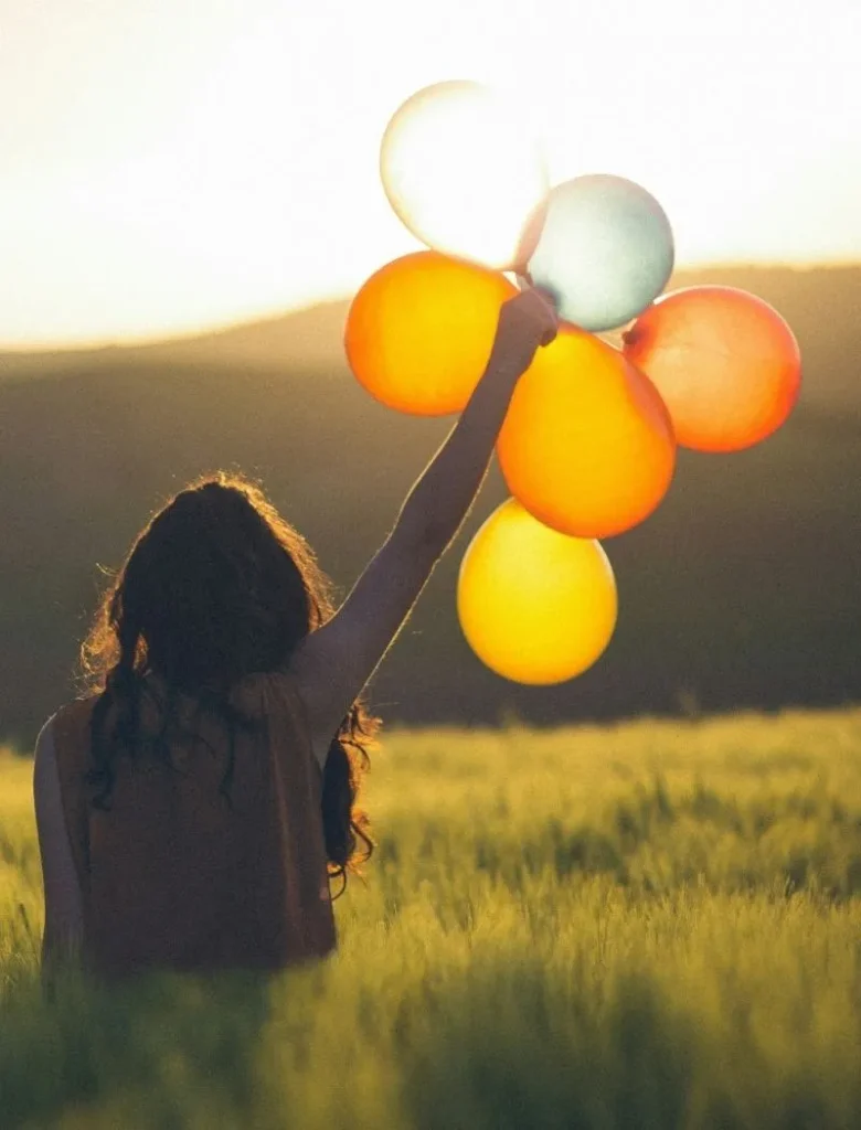 woman holding balloons in a grass field