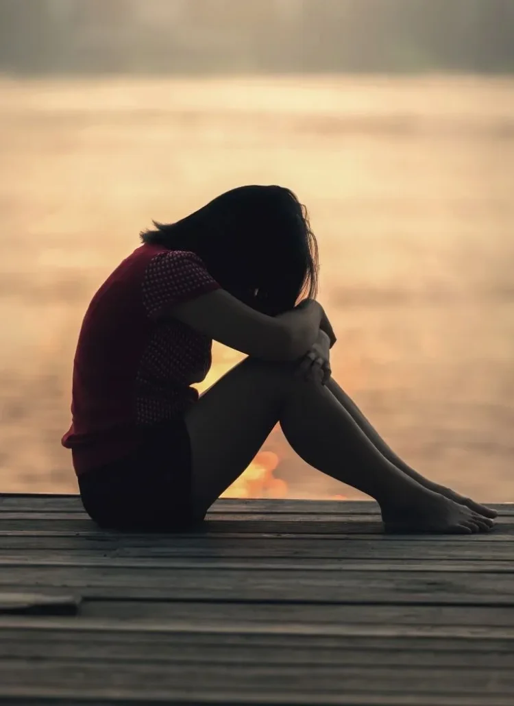 sad woman sitting by water after a breakup