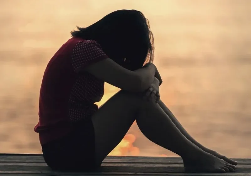 sad woman sitting by water after a breakup