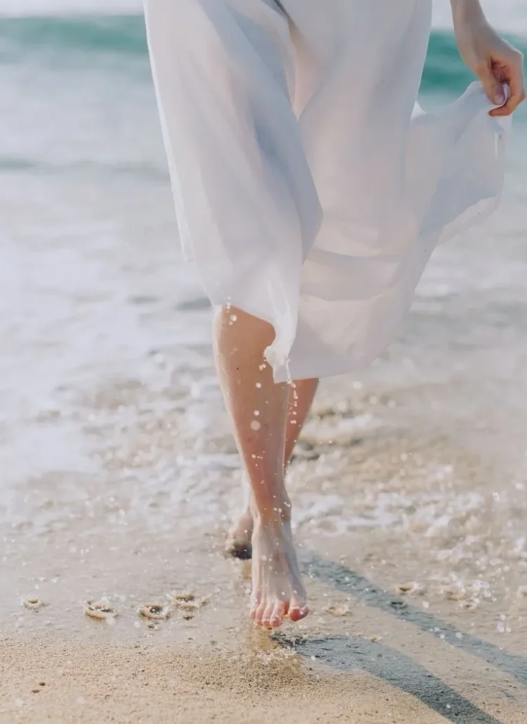 woman walking barefoot by the water