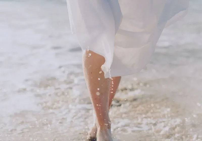 woman walking barefoot by the water