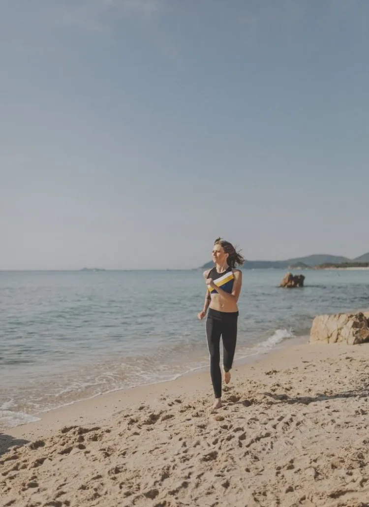 woman running barefoot by the beach
