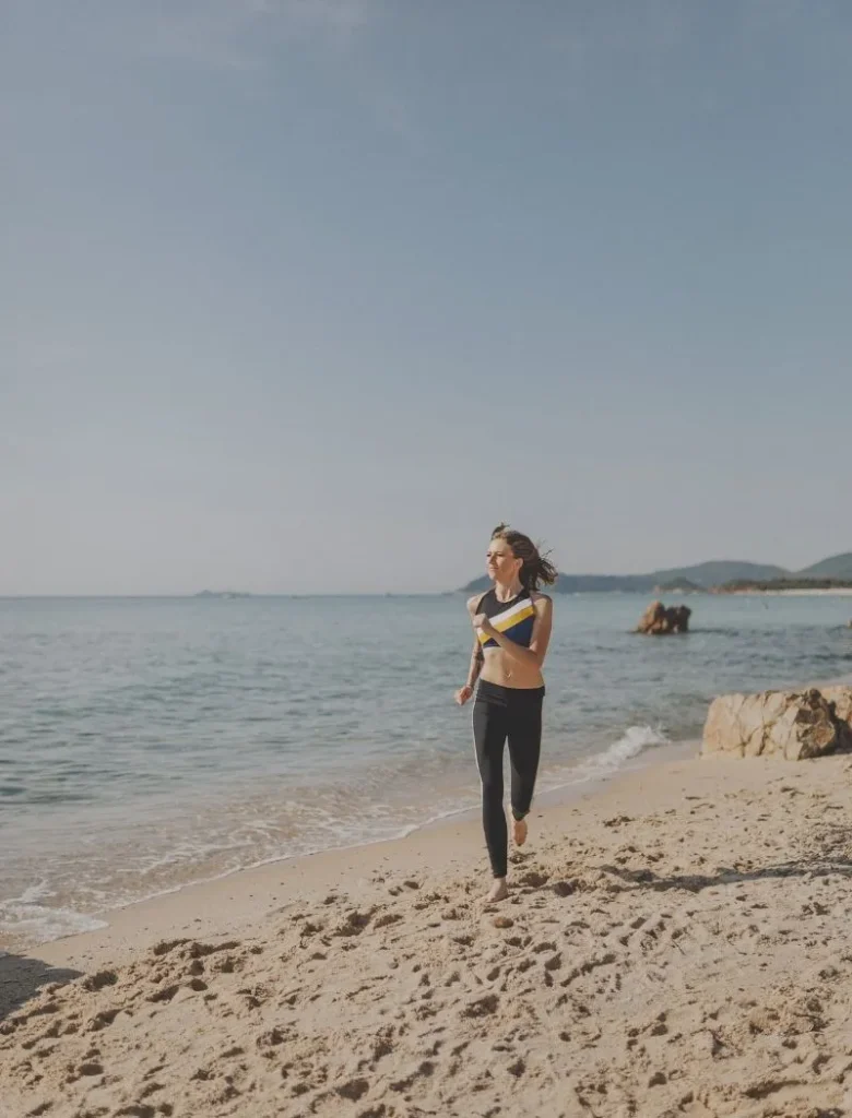woman running barefoot by the beach