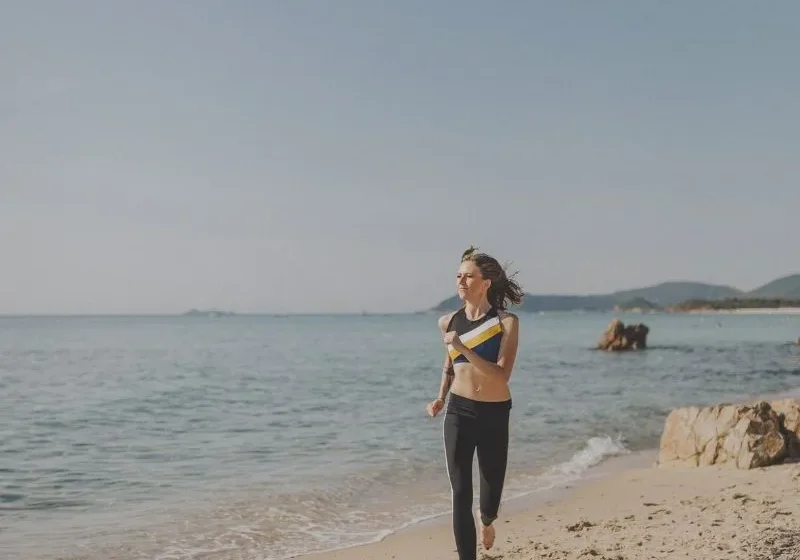 woman running barefoot by the beach