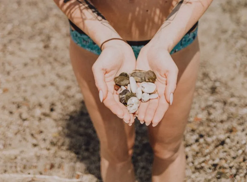 woman holding sea shells she found at the beach - a summer activity for adult