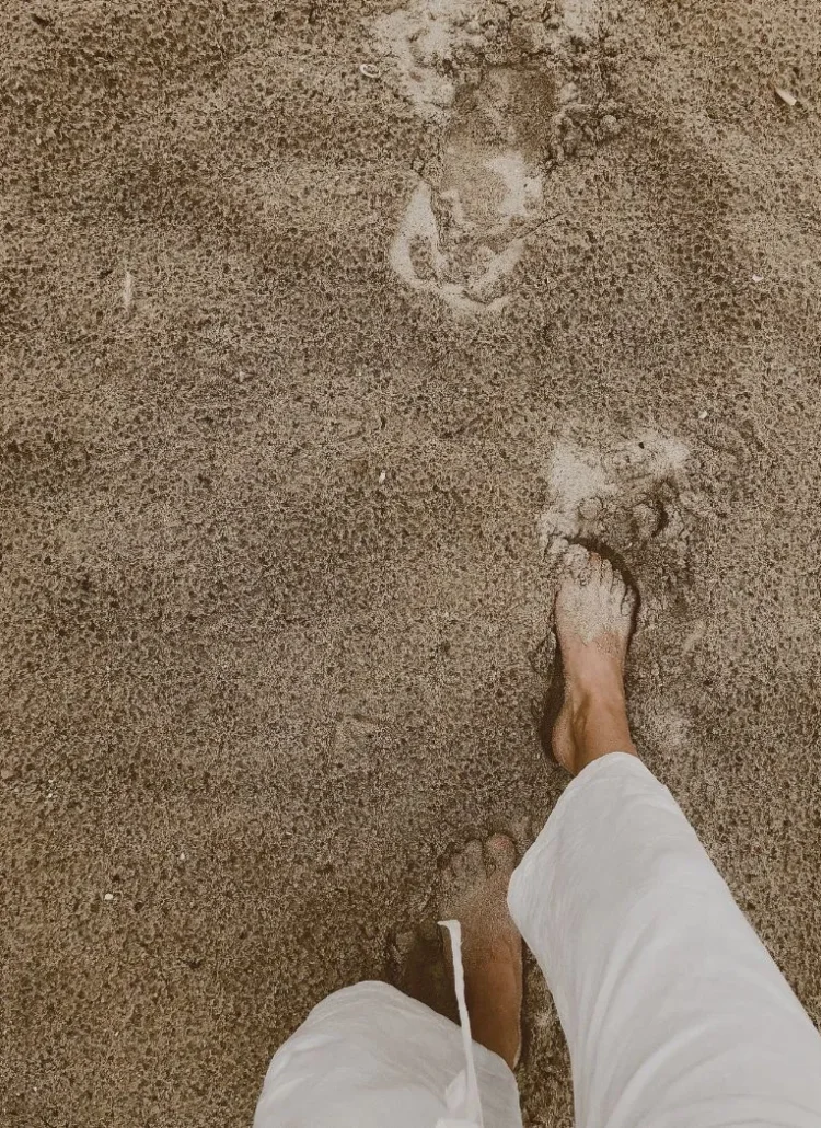 woman wearing white pants walking on the beach