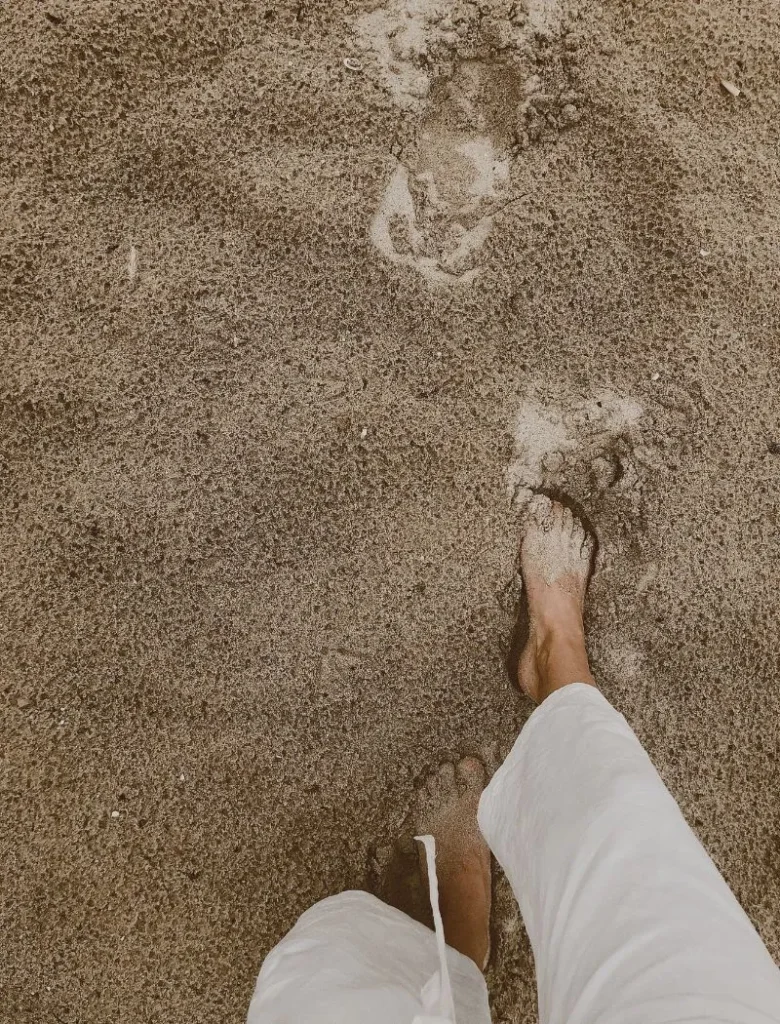 woman wearing white pants walking on the beach