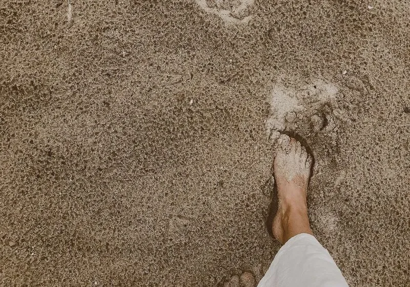 woman wearing white pants walking on the beach