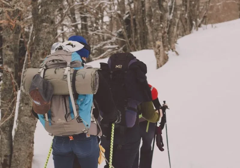 a group of people hiking in the snow - a winter bucket list activity to do for adults