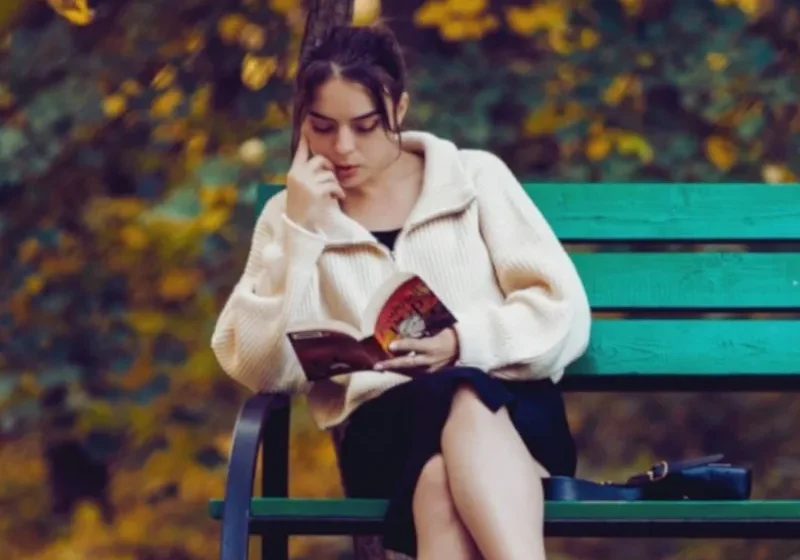 Woman doing fall solo activities. She's reading by herself at the park