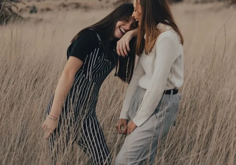 two girl friends laughing in the middle of a field
