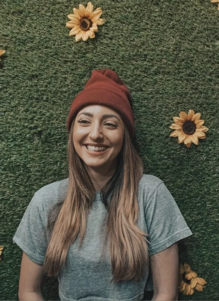 happy woman smiling with a grass and sunflower backdrop