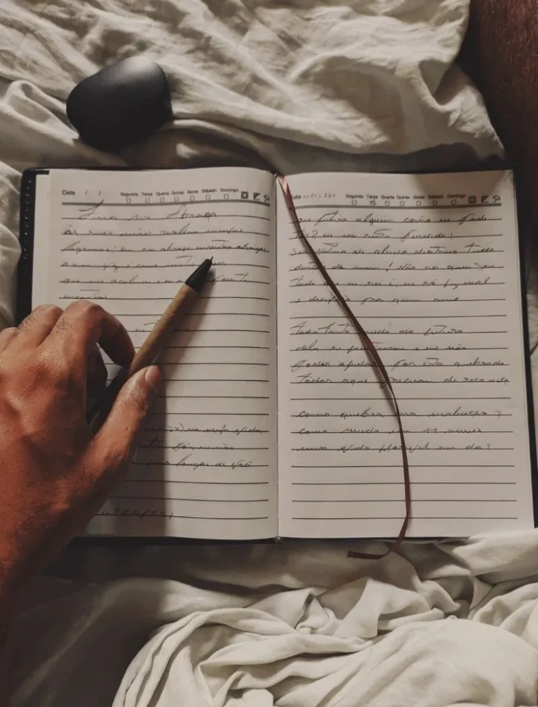 a hand holding a pen on top of a journal book