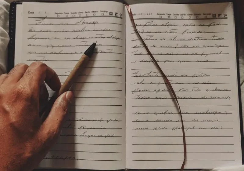 a hand holding a pen on top of a journal book