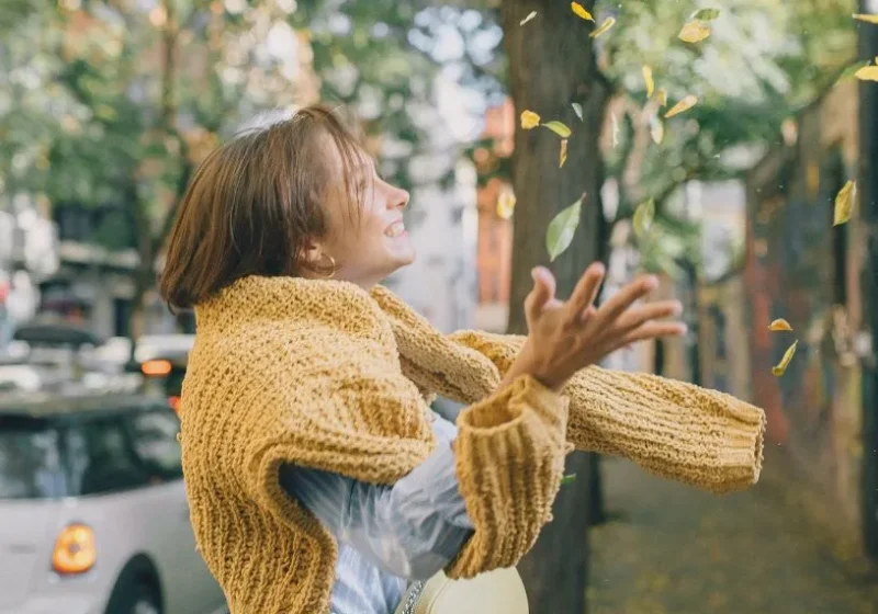 woman enjoying her best self throwing fall leaves