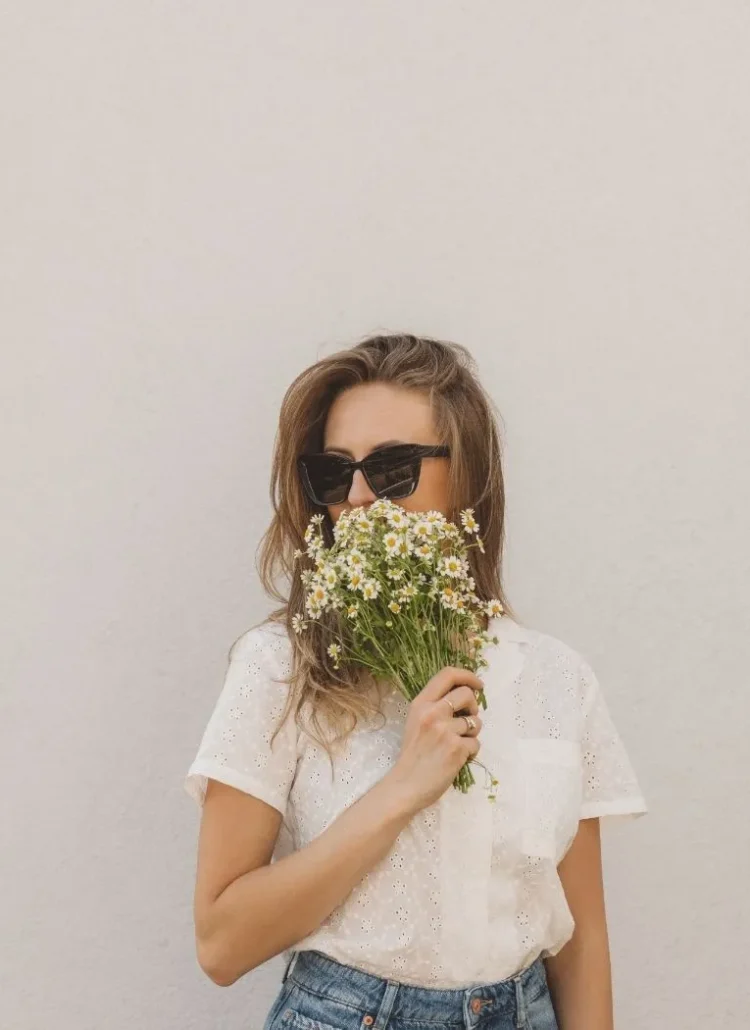 woman with sunglasses and flowers in her hand