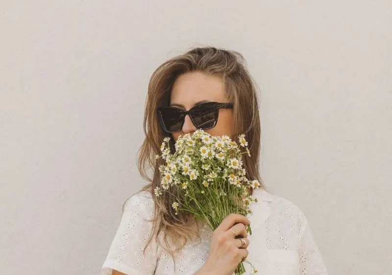 woman with sunglasses and flowers in her hand