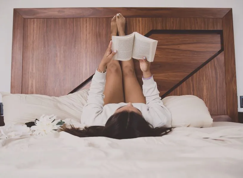 woman reading in bed as part of her bedtime routine of no digitals and better sleep