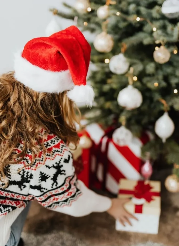 woman wearing xmas hat putting gifts under the Christmas tree