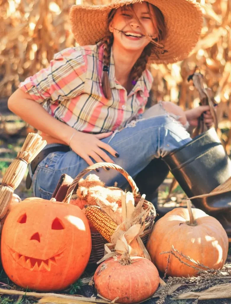 woman in happy halloween spirit sitting behind pumpkins and jack-o-lantern