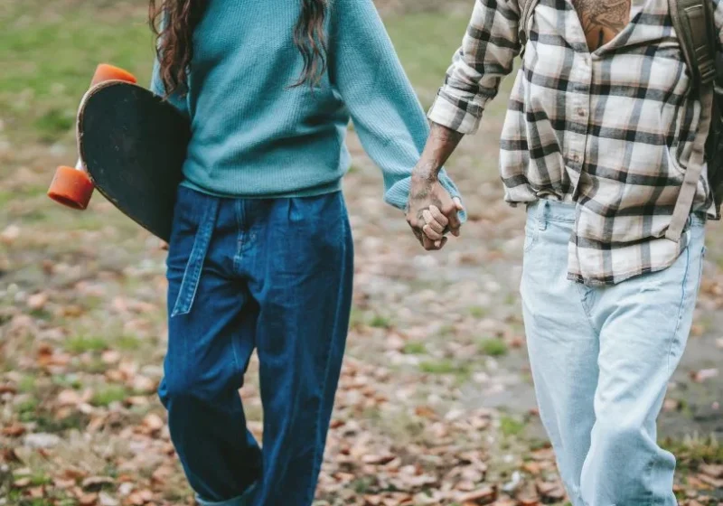 couple holding hands with skateboard in their hands