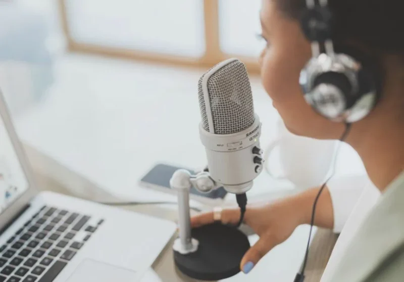 woman speaking on a speaker with headset on and a laptop in front of her