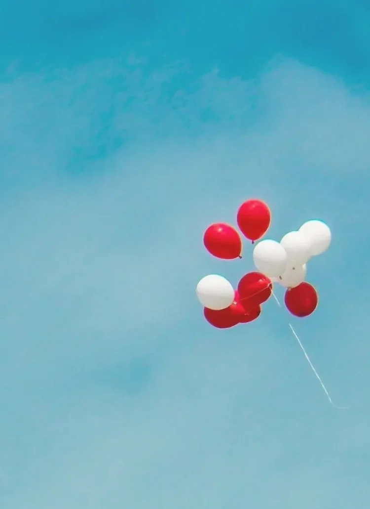red and white balloons floating in the sky