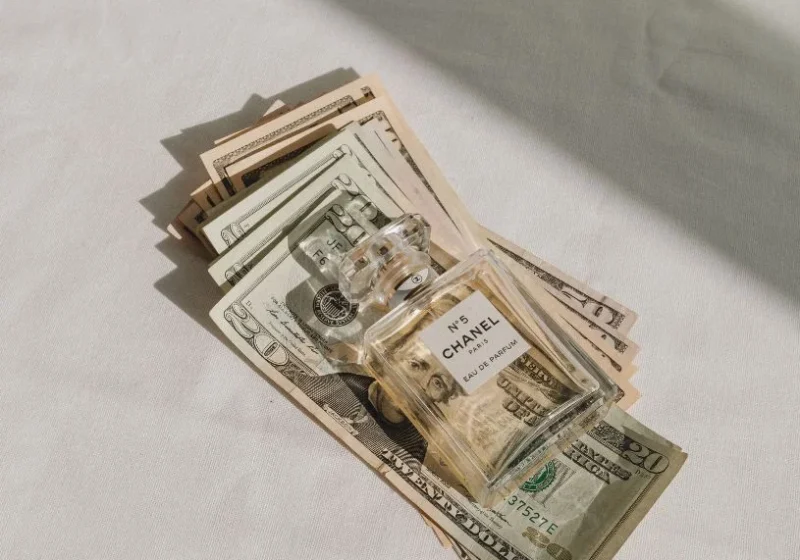 chanel perfume bottle on top of dollar bills