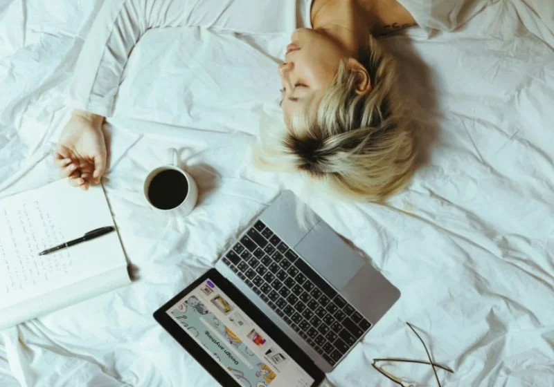 woman laying in bed with coffee and laptop
