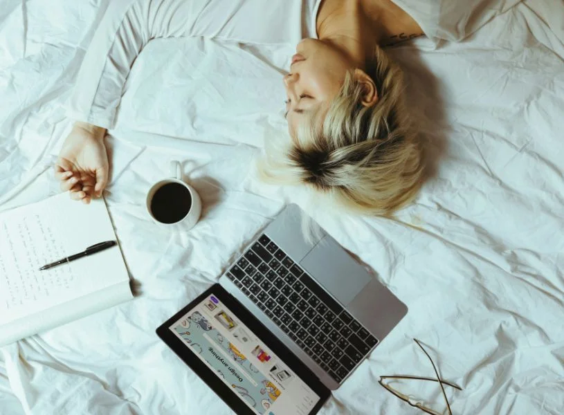 woman laying in bed with coffee and laptop