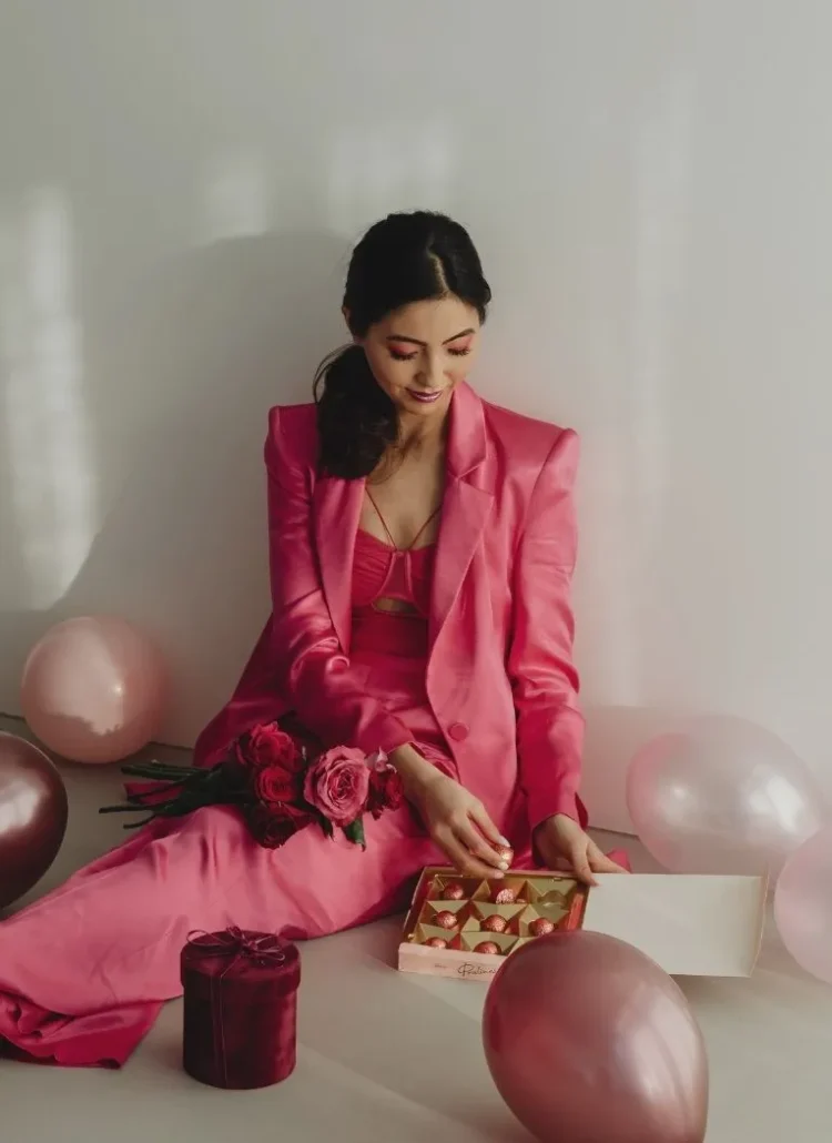 women dressed in pink sitting on the floor with balloons and chocolates