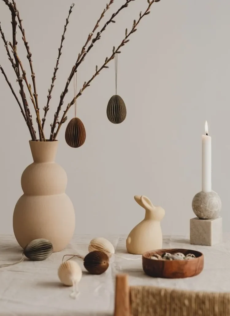 Easter decor with bunny, candle and easter tree and eggs in wooden container. All in earthy muted tone
