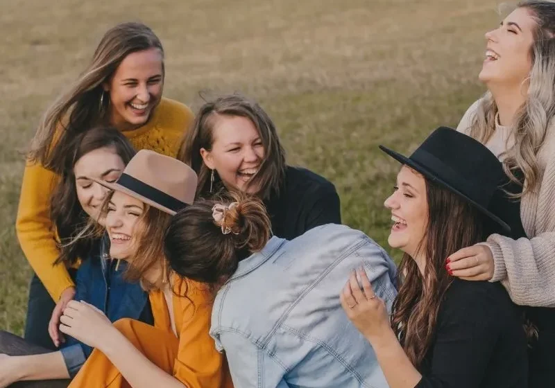 a group of women laughing sitting on the grass