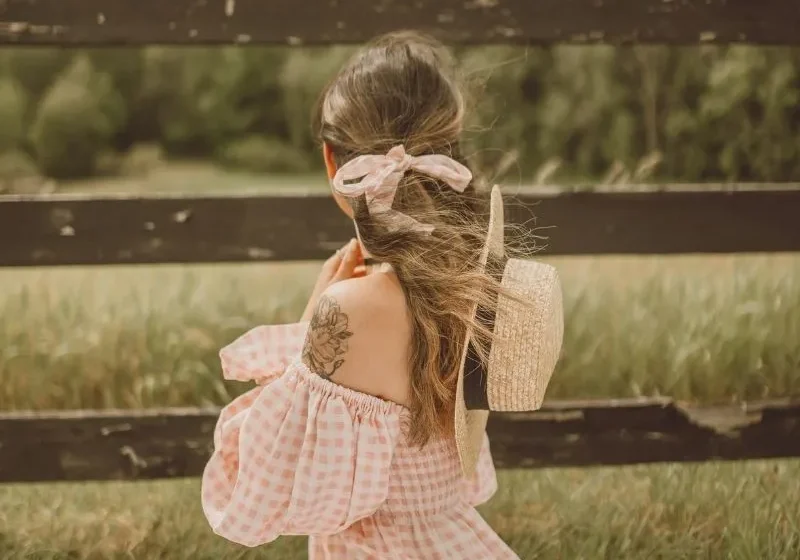 woman having a solo picnic in checkered pink and white dress looking out to the horizon
