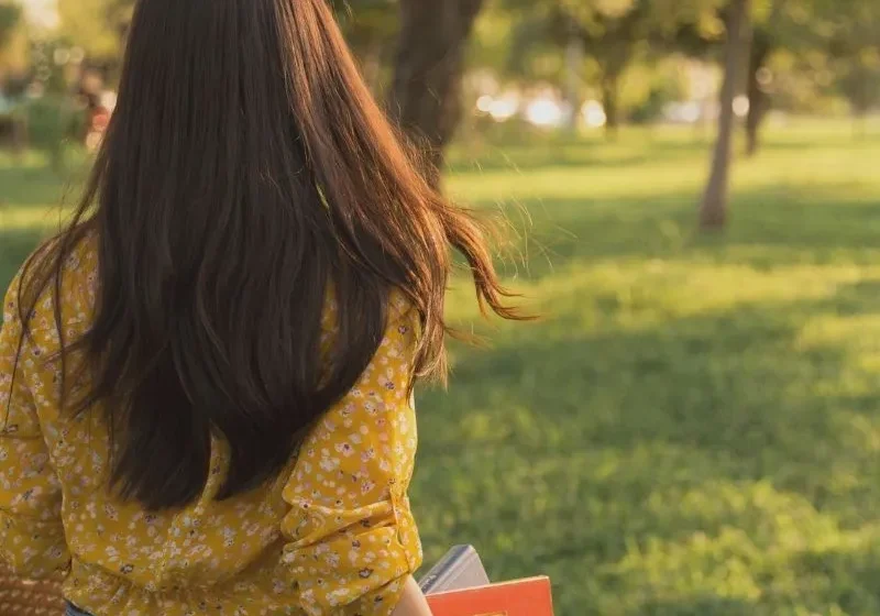 young woman walking in the park with books