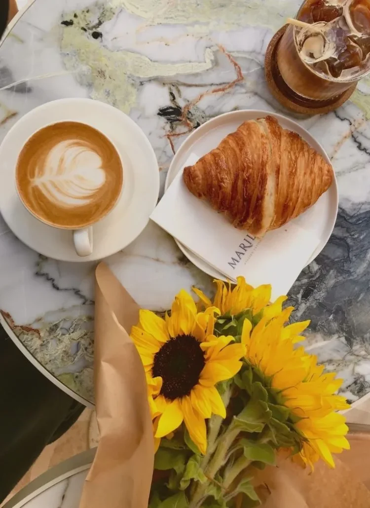 sunflower on marble table with coffee, and croissant