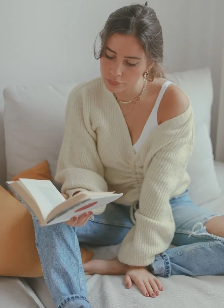 woman in white cardigan reading a book