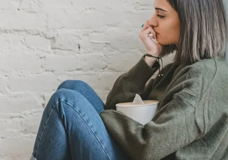 brown hair woman sitting by the wall with tissue box in her hand