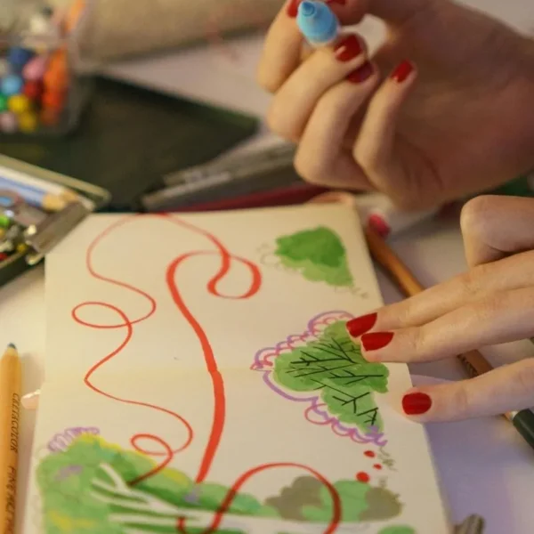 woman with red nails doing art journaling.