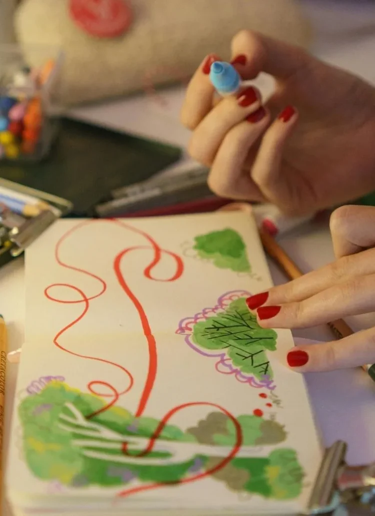 woman with red nails doing art journaling.