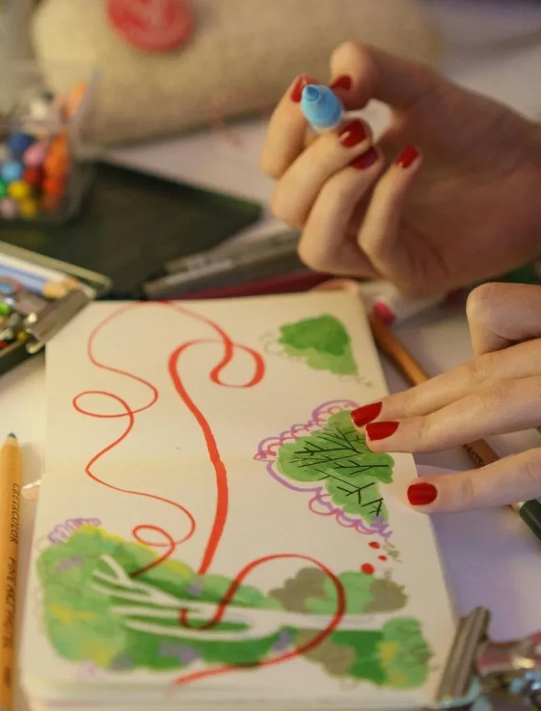 woman with red nails doing art journaling.